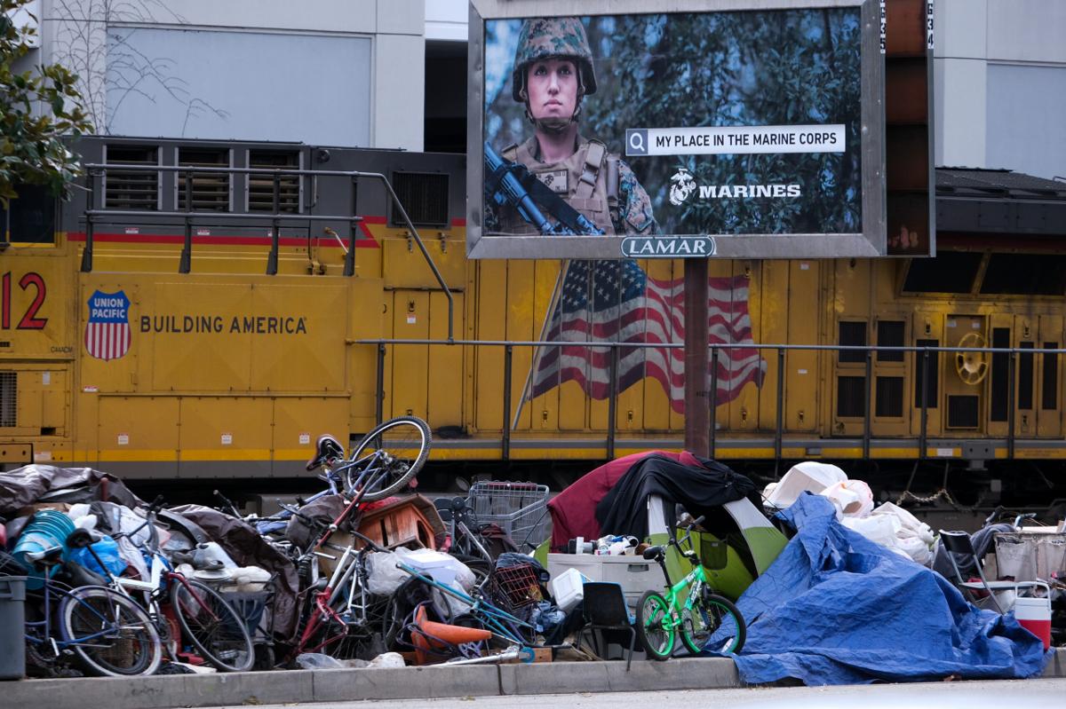 A Marine Corps billboard stands over a homeless encampment in Los Angeles.